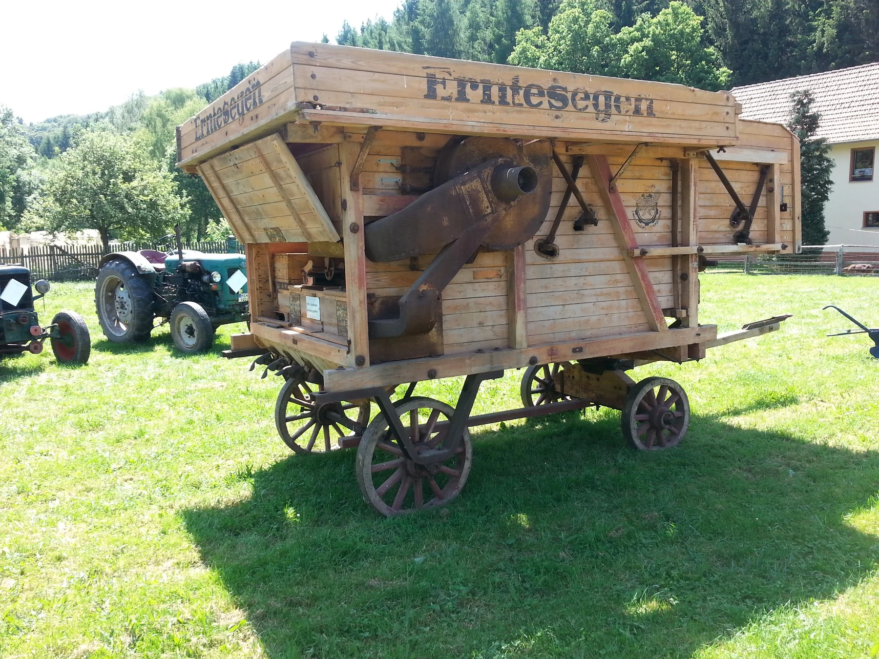 Hölzerne landwirtschaftliche Maschine auf vier Rädern mit dem Schriftzug Erntesegen